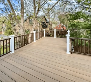 Wooden deck with railing, overlooking trees and houses on a sunny day.