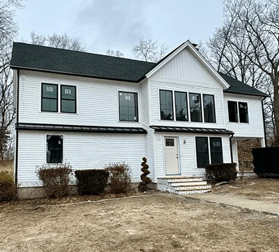 A white two-story house with black shutters, numbered 59, on a barren landscape with a cloudy sky.